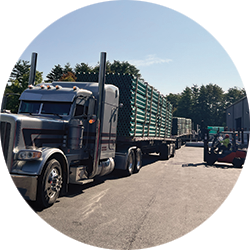 Flatbed truck delivering steel and pipe products to a wholesale distribution yard for receiving and inventory replenishment.